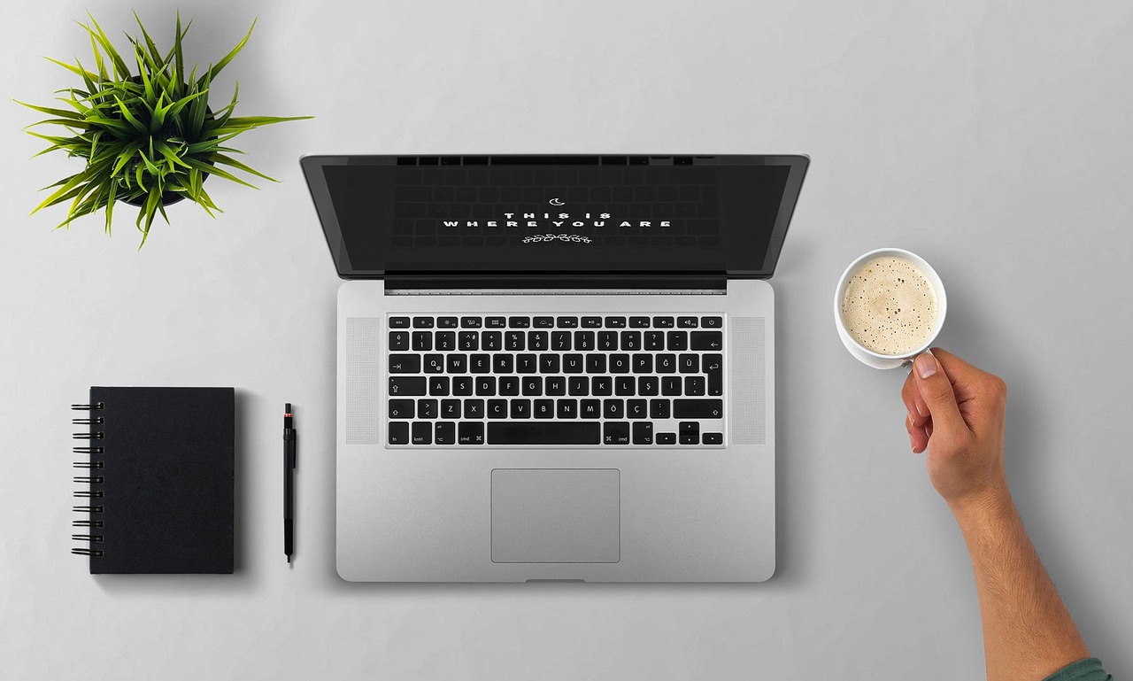 Laptop, coffee, arm, desktop, and notebook visible
